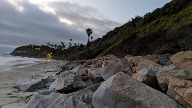 Swamis Sahili 'nin sanatsal erimiş kayaları. 50 yıl önce kıyı boyunca uzanan erozyon kontrol kayaları Swamis Resif Sörf Parkı Encinitas California 'daki dalga enerjili kaya parlatıcı ekibindeki çok renkli nehir kayalarıyla çevrili..