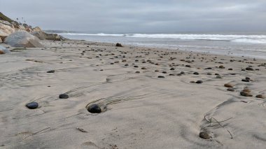 Swamis Sahili 'nin soğuk erimiş kayaları. 50 yıl önce kıyı şeridi boyunca uzanan okyanus dalgası erozyon kontrol taşları Swamis Resif Sörf Parkı Encinitas California 'daki antik nehir kayaları ve soyut heykellere benziyor..