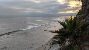 Swamis Sahili 'nde gün batımı gökyüzü. Güney Kaliforniya 'nın ücra kumsalları, gün batımları, sörfçüler, gelgit havuzları, dalgalar yontulmuş kayalar, palmiye ağaçları ve San Diego' nun 25 mil kuzeyindeki Encinitas Kayalık Sörf Parkı 'nda şiddetli kış fırtınaları..