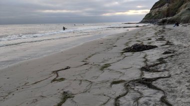 Swamis Sahili 'nde gün batımı gökyüzü. Güney Kaliforniya 'nın ücra kumsalları, gün batımları, sörfçüler, gelgit havuzları, dalgalar yontulmuş kayalar, palmiye ağaçları ve San Diego' nun 25 mil kuzeyindeki Encinitas Kayalık Sörf Parkı 'nda şiddetli kış fırtınaları..