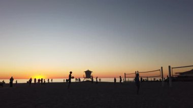 San Diego yakınlarındaki Güney Kaliforniya plaj sahneleri - Günbatımı ve martılar, sörfçüler, voleybol siluetleri, gelgit havuzları, dalgalar, kayalar, kumsallar ve Encinitas California 'daki Moonlight Sahili' ndeki palmiye ağaçları.