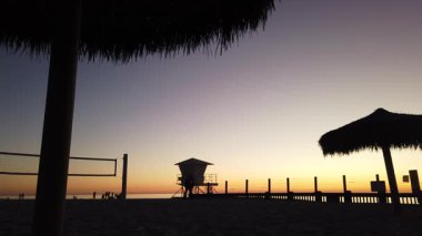 San Diego yakınlarındaki Güney Kaliforniya plaj sahneleri - Günbatımı ve martılar, sörfçüler, voleybol siluetleri, gelgit havuzları, dalgalar, kayalar, kumsallar ve Encinitas California 'daki Moonlight Sahili' ndeki palmiye ağaçları.