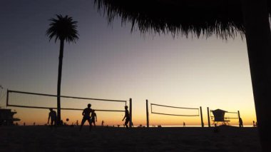 San Diego yakınlarındaki Güney Kaliforniya plaj sahneleri - Günbatımı ve martılar, sörfçüler, voleybol siluetleri, gelgit havuzları, dalgalar, kayalar, kumsallar ve Encinitas California 'daki Moonlight Sahili' ndeki palmiye ağaçları.