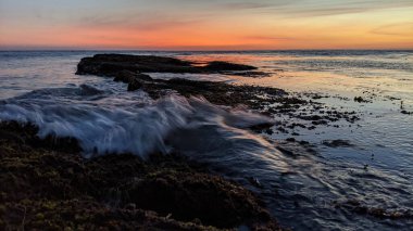 Günbatımında Güney Kaliforniya sahillerinde, eski resif gel-git havuzları, okyanus dalgaları ve Swamis Resif Parkı Encinitas California 'da alacakaranlık renkli gökyüzü.