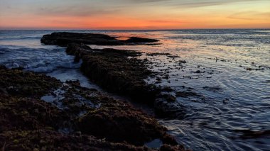 Günbatımında Güney Kaliforniya sahillerinde, eski resif gel-git havuzları, okyanus dalgaları ve Swamis Resif Parkı Encinitas California 'da alacakaranlık renkli gökyüzü.