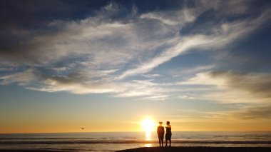 Güney Kaliforniya sahili siluetleri, sörfçüler, gelgit havuzları ve palmiye ağaçları Swamis Kayalık Sörf Parkı, Ay ışığı ve Encinitas California 'daki Cardiff plajları.