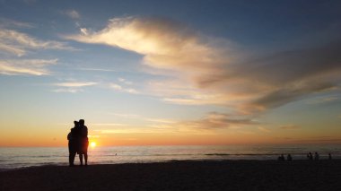 Güney Kaliforniya sahili siluetleri, sörfçüler, gelgit havuzları ve palmiye ağaçları Swamis Kayalık Sörf Parkı, Ay ışığı ve Encinitas California 'daki Cardiff plajları.