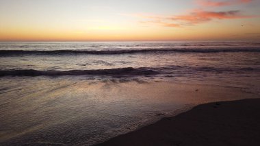 Güney Kaliforniya sahili, San Diego 'nun kuzeyi. Günbatımları, sörfçüler, gelgit havuzları, dalgalar, kayalar, kum, yosun ve palmiye ağaçları Encinitas California 'daki Swamis Resif Sörf Parkı' nda..