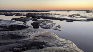 San Diego 'nun kuzeyinde Güney Kaliforniya sahilleri - Encinitas Kaliforniya' daki Swamis Resif Sörf Parkı 'nda günbatımı, sörfçüler, gelgit havuzları, dalgalar, kayalar, kum ve palmiye ağaçları.