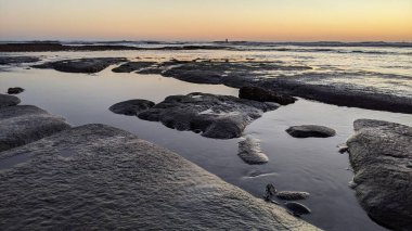 San Diego 'nun kuzeyinde Güney Kaliforniya sahilleri - Encinitas Kaliforniya' daki Swamis Resif Sörf Parkı 'nda günbatımı, sörfçüler, gelgit havuzları, dalgalar, kayalar, kum ve palmiye ağaçları.