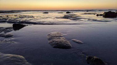 San Diego 'nun kuzeyinde Güney Kaliforniya sahilleri - Encinitas Kaliforniya' daki Swamis Resif Sörf Parkı 'nda günbatımı, sörfçüler, gelgit havuzları, dalgalar, kayalar, kum ve palmiye ağaçları.