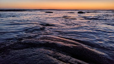 San Diego 'nun kuzeyinde Güney Kaliforniya sahilleri - Encinitas Kaliforniya' daki Swamis Resif Sörf Parkı 'nda günbatımı, sörfçüler, gelgit havuzları, dalgalar, kayalar, kum ve palmiye ağaçları.