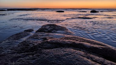 San Diego 'nun kuzeyinde Güney Kaliforniya sahilleri - Encinitas Kaliforniya' daki Swamis Resif Sörf Parkı 'nda günbatımı, sörfçüler, gelgit havuzları, dalgalar, kayalar, kum ve palmiye ağaçları.