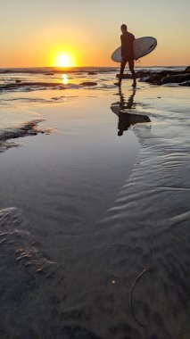 Günbatımları, sörfçüler, gelgit havuzları, palmiye ağaçları ve Swamis Resif Parkı Encinitas California sahilindeki doğal yontulmuş plaj kayaları olan Güney Kaliforniya sahili manzarası..