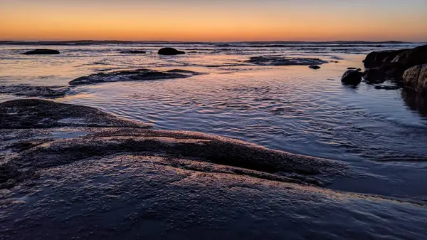 San Diego 'nun kuzeyinde Güney Kaliforniya sahilleri - Encinitas Kaliforniya' daki Swamis Resif Sörf Parkı 'nda günbatımı, sörfçüler, gelgit havuzları, dalgalar, kayalar, kum ve palmiye ağaçları.