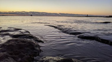 Swamis Resif Parkı Encinitas 'ta gelgit havuzları, okyanus dalgaları ve alacakaranlık renkli gökyüzü olan antik bir resifte günbatımı sörf sahnesi..
