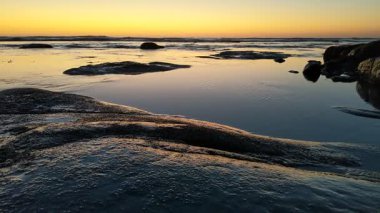 San Diego yakınlarındaki Güney Kaliforniya plaj sahneleri - Encinitas California 'daki Swamis Resif Sörf Parkı' nda günbatımı, sörfçüler, gelgit havuzları, dalgalar, kayalar, kum ve palmiye ağaçları.