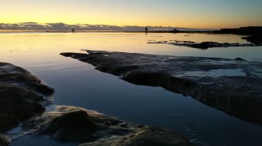 San Diego yakınlarındaki Güney Kaliforniya plaj sahneleri - Encinitas California 'daki Swamis Resif Sörf Parkı' nda günbatımı, sörfçüler, gelgit havuzları, dalgalar, kayalar, kum ve palmiye ağaçları.