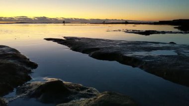 San Diego yakınlarındaki Güney Kaliforniya plaj sahneleri - Encinitas California 'daki Swamis Resif Sörf Parkı' nda günbatımı, sörfçüler, gelgit havuzları, dalgalar, kayalar, kum ve palmiye ağaçları.