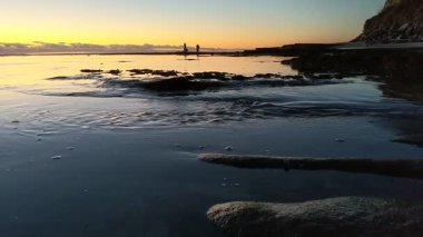 San Diego yakınlarındaki Güney Kaliforniya plaj sahneleri - Encinitas California 'daki Swamis Resif Sörf Parkı' nda günbatımı, sörfçüler, gelgit havuzları, dalgalar, kayalar, kum ve palmiye ağaçları.