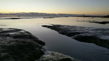 Güney Kaliforniya plaj manzarası - Encinitas California 'daki Swamis Resif Sörf Parkı' nda günbatımı, sörfçüler, gelgit havuzları, dalgalar, kayalar, kum ve palmiye ağaçları.
