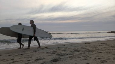 San Diego yakınlarındaki Güney Kaliforniya plajları. Encinitas kıyılarındaki Swamis Resif Sörf Parkı 'nda gün batımları, sörfçüler, gelgit havuzları ve palmiye ağaçları.