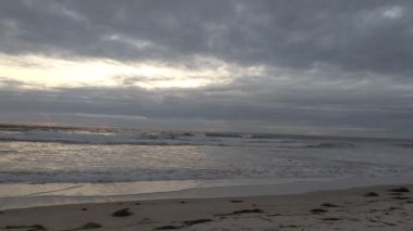 Güney Kaliforniya plaj manzarası - Encinitas California 'daki Swamis Resif Sörf Parkı' nda günbatımı, sörfçüler, gelgit havuzları, dalgalar, kayalar, kum ve palmiye ağaçları.