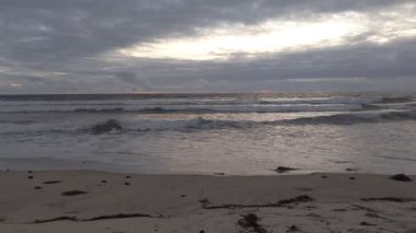 Güney Kaliforniya plaj manzarası - Encinitas California 'daki Swamis Resif Sörf Parkı' nda günbatımı, sörfçüler, gelgit havuzları, dalgalar, kayalar, kum ve palmiye ağaçları.