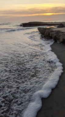 Pasifik kıyıları eski resifler, gelgit havuzları, okyanus dalgaları, palmiye ağaçları, sörf tahtaları ve deniz kuşlarının yanı sıra sıcak görünüşlü günbatımı gökyüzü ve Swamis Resif Parkı Encinitas güney Kaliforniya 'daki kaya soyutlamaları ile güzel manzaralar..