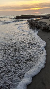 Pasifik kıyıları eski resifler, gelgit havuzları, okyanus dalgaları, palmiye ağaçları, sörf tahtaları ve deniz kuşlarının yanı sıra sıcak görünüşlü günbatımı gökyüzü ve Swamis Resif Parkı Encinitas güney Kaliforniya 'daki kaya soyutlamaları ile güzel manzaralar..