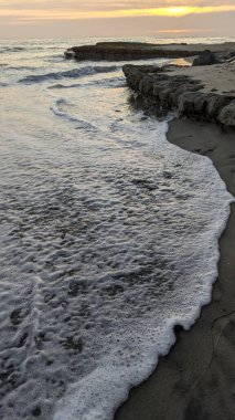 Pasifik kıyıları eski resifler, gelgit havuzları, okyanus dalgaları, palmiye ağaçları, sörf tahtaları ve deniz kuşlarının yanı sıra sıcak görünüşlü günbatımı gökyüzü ve Swamis Resif Parkı Encinitas güney Kaliforniya 'daki kaya soyutlamaları ile güzel manzaralar..