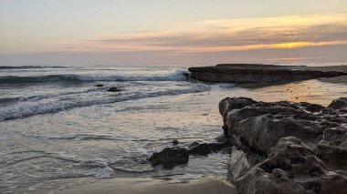 Pasifik kıyıları eski resifler, gelgit havuzları, okyanus dalgaları, palmiye ağaçları, sörf tahtaları ve deniz kuşlarının yanı sıra sıcak görünüşlü günbatımı gökyüzü ve Swamis Resif Parkı Encinitas güney Kaliforniya 'daki kaya soyutlamaları ile güzel manzaralar..