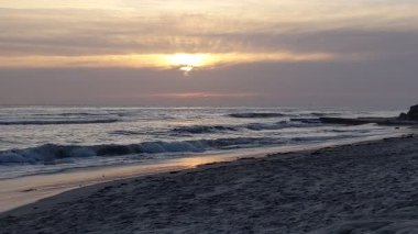 San Diego 'nun kuzeyindeki Güney Kaliforniya plaj sahneleri - Encinitas California' daki Swamis Resif Sörf Parkı 'ndaki altın günbatımları, sörfçüler, gelgit havuzları, dalgalar, kayalar, kumlu plajlar ve palmiye ağaçları.