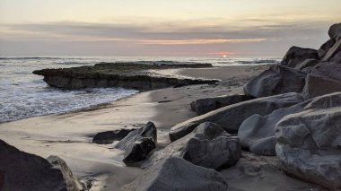Pasifik kıyıları eski resifler, gelgit havuzları, okyanus dalgaları, palmiye ağaçları, sörf tahtaları ve deniz kuşlarının yanı sıra sıcak görünüşlü günbatımı gökyüzü ve Swamis Resif Parkı Encinitas güney Kaliforniya 'daki kaya soyutlamaları ile güzel manzaralar..