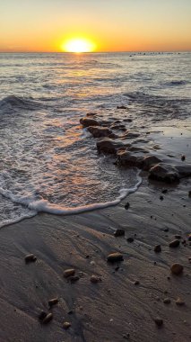 Swamis Sahili 'nde Sunset Sky. Güney Kaliforniya 'nın ücra kumsalları, günbatımları, sörfçüler, gelgit havuzları, dalgalar yontulmuş kayalar, palmiye ağaçları ve San Diego' nun 25 mil kuzeyindeki Encinitas Kayalık Sörf Parkı 'ndaki kış fırtınaları..