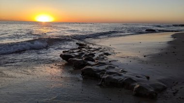 Swamis Sahili 'nde Sunset Sky. Güney Kaliforniya 'nın ücra kumsalları, günbatımları, sörfçüler, gelgit havuzları, dalgalar yontulmuş kayalar, palmiye ağaçları ve San Diego' nun 25 mil kuzeyindeki Encinitas Kayalık Sörf Parkı 'ndaki kış fırtınaları..