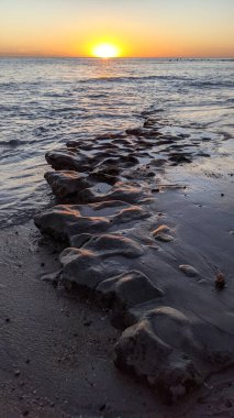 Swamis Sahili 'nde Sunset Sky. Güney Kaliforniya 'nın ücra kumsalları, günbatımları, sörfçüler, gelgit havuzları, dalgalar yontulmuş kayalar, palmiye ağaçları ve San Diego' nun 25 mil kuzeyindeki Encinitas Kayalık Sörf Parkı 'ndaki kış fırtınaları..