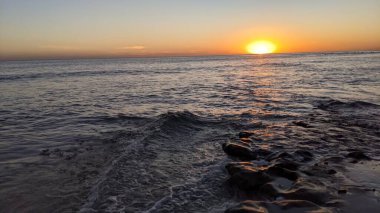 Swamis Sahili 'nde Sunset Sky. Güney Kaliforniya 'nın ücra kumsalları, günbatımları, sörfçüler, gelgit havuzları, dalgalar yontulmuş kayalar, palmiye ağaçları ve San Diego' nun 25 mil kuzeyindeki Encinitas Kayalık Sörf Parkı 'ndaki kış fırtınaları..