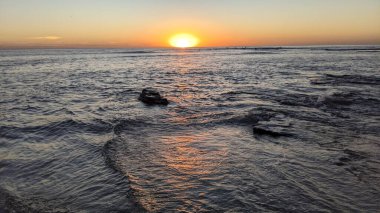 Günbatımında Güney Kaliforniya plaj sahneleri. Swamis Resif Parkı Encinitas California 'da okyanus resifi gel-git havuzları, dalgalar ve karanlık gökyüzü..