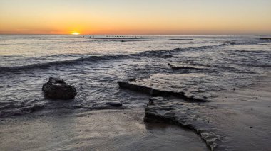 Günbatımında Güney Kaliforniya plaj sahneleri. Antik resif gel-git havuzları, okyanus dalgaları ve Swamis Kayalık Sörf Parkı Encinitas California 'da alacakaranlık renkli gökyüzü..