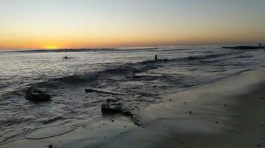 San Diego 'nun kuzeyindeki Güney Kaliforniya plaj sahneleri - Encinitas California' daki Swamis Resif Sörf Parkı 'ndaki altın günbatımları, sörfçüler, gelgit havuzları, dalgalar, kayalar, kumlu plajlar ve palmiye ağaçları.