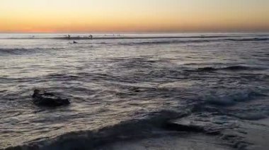 San Diego 'nun kuzeyindeki Güney Kaliforniya plaj sahneleri - Encinitas California' daki Swamis Resif Sörf Parkı 'ndaki altın günbatımları, sörfçüler, gelgit havuzları, dalgalar, kayalar, kumlu plajlar ve palmiye ağaçları.