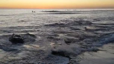 Güney Kaliforniya tenha plajları, altın gün batımları, okyanus dalgaları, sörfçüler, gelgit havuzları ve Encinitas California 'daki Swamis Resif Sörf Parkı' ndaki palmiye ağaçları..