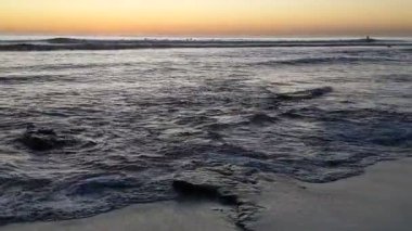 Güney Kaliforniya tenha plajları, altın gün batımları, okyanus dalgaları, sörfçüler, gelgit havuzları ve Encinitas California 'daki Swamis Resif Sörf Parkı' ndaki palmiye ağaçları..