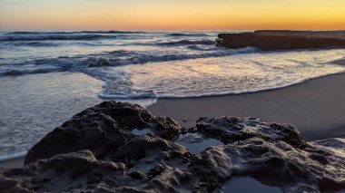 Günbatımında Güney Kaliforniya plaj manzarası. Antik resifler, gel-git havuzları, okyanus dalgaları, sörfçüler ve Swamis Resif Parkı Encinitas California 'da sıcak renkli gökyüzü..