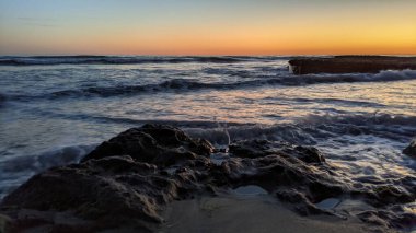 Günbatımında Güney Kaliforniya plaj manzarası. Antik resifler, gel-git havuzları, okyanus dalgaları, sörfçüler ve Swamis Resif Parkı Encinitas California 'da sıcak renkli gökyüzü..