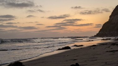 Swamis Resif Parkı Encinitas California 'da gelgit havuzları, soyut kaya oluşumları, okyanus dalgaları, sörfçüler ve sıcak renkli gökyüzü ile günbatımında Güney Kaliforniya plaj sahneleri.