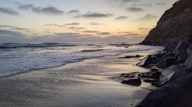 Güney Kaliforniya plaj sahneleri, gelgit havuzları, soyut kaya oluşumları, okyanus dalgaları, sörf tahtaları, palmiye ağaçları ve Swamis Resif Parkı Encinitas California 'da sıcak lavanta gökyüzü..