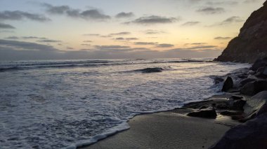 Güney Kaliforniya plaj sahneleri, gelgit havuzları, soyut kaya oluşumları, okyanus dalgaları, sörf tahtaları, palmiye ağaçları ve Swamis Resif Parkı Encinitas California 'da sıcak lavanta gökyüzü..