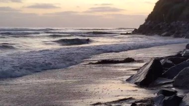 Günbatımında Güney Kaliforniya plaj sahneleri gelgit havuzları, siluetler, soyut kaya oluşumları, okyanus dalgaları, sörf tahtalı sörfçüler ve Swamis Resif Parkı Encinitas California 'da sıcak güneşli gökyüzü.